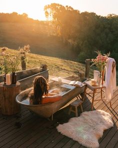 a dog sitting in a bathtub on top of a wooden deck next to a table