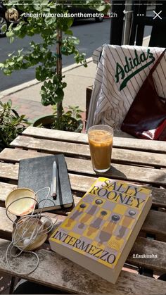 a book sitting on top of a wooden bench next to a cup and saucer