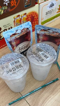 three plastic containers with food on top of a wooden table next to chopsticks