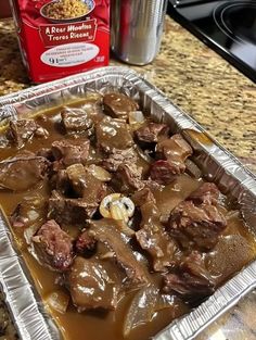 a pan filled with meat and gravy on top of a counter