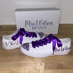 a pair of white shoes with purple bows are on the floor next to a box