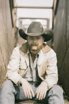 a man wearing a cowboy hat sitting on the ground