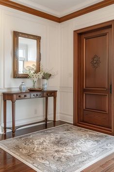 a room with a rug, table and mirror on the wall next to an open door