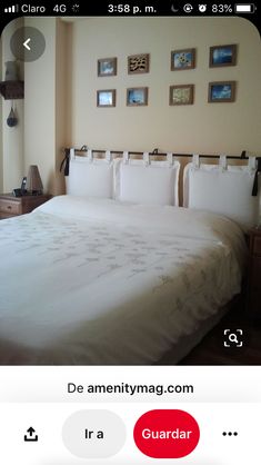 a bed with white sheets and pillows in a bedroom next to a wall with pictures on it