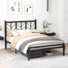 a bedroom with white walls and wooden flooring has a black metal bed frame, two nightstands on either side