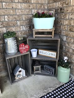 two wooden crates with flowers and plants on them sitting in front of a brick wall