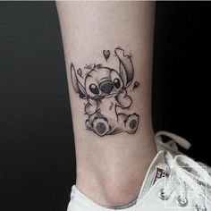 a small tattoo on the ankle of a person with a koala bear and hearts