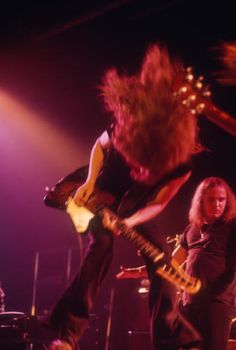 two people on stage with guitars and one person playing the guitar in front of them