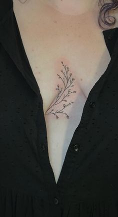 a woman's chest with a small tattoo on her left side and flowers in the middle