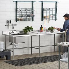 a man standing in front of a kitchen sink filled with lots of vegetables and cooking utensils