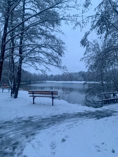 a park bench sitting next to a lake covered in snow