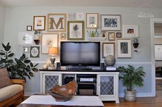 a living room filled with furniture and lots of framed pictures on the wall above it