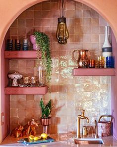 a kitchen with pink walls and shelves filled with pots, pans and other items