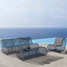 an outdoor lounge set with two chairs and a coffee table next to the pool overlooking the ocean