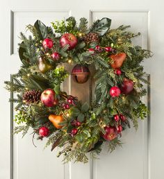 a christmas wreath on the front door with apples, holly and pomegranates