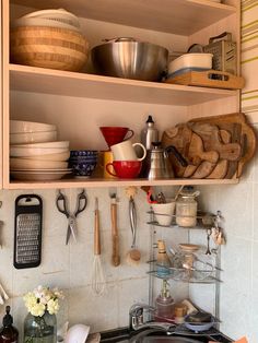 the shelves above the kitchen sink are filled with pots, pans and utensils