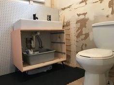 a white toilet sitting in a bathroom next to a wooden cabinet with items inside it