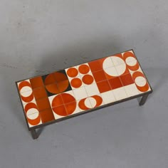 an orange and white coffee table with circles on it's sides, against a gray background