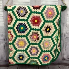 a green and white quilt hanging on a wall next to a wooden door with flowers