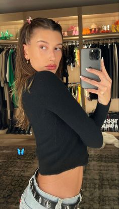 a young woman taking a selfie in front of a closet with clothes on hangers