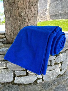 a blue towel sitting on top of a stone wall next to a tree