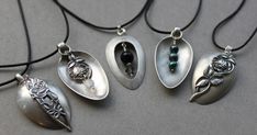 four necklaces with different designs on them sitting on a gray surface, one is silver and the other is black