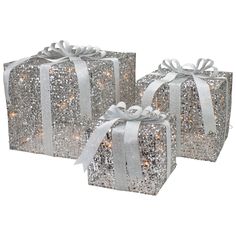 three silver gift boxes with white bows and lights on them, both wrapped in glitter