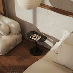 two white couches and a small table in a room with wood flooring on the side