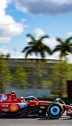 a red race car driving on a track with palm trees in the backgroud