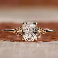 a cushion cut diamond sits on top of a wooden surface in an antique style setting