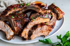 some meat on a white plate with sauce and parsley around the edges, ready to be eaten