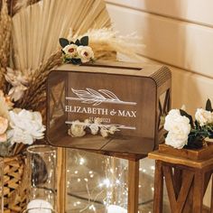 a wooden box sitting on top of a table next to candles and flowers in vases