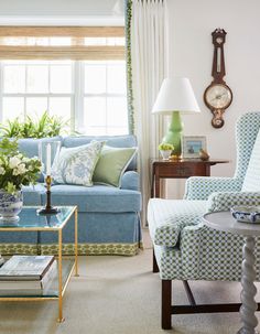 a living room filled with furniture and a clock on the wall above it's windows