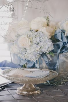 there are flowers in vases on the table with silver plates and utensils