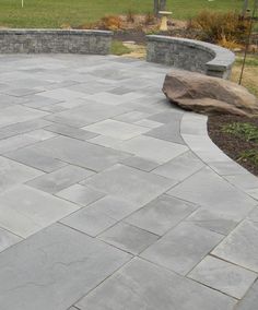 an outdoor patio with stone walls and seating area in the background, surrounded by grass