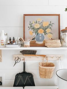 a shelf filled with lots of different items on top of a white wall next to a potted plant