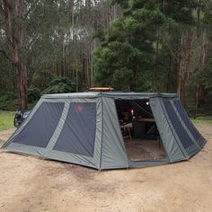 a tent set up in the middle of a forest with two bikes parked inside it