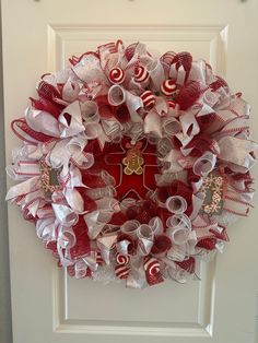 a red and white christmas wreath with candy canes hanging on the front door,