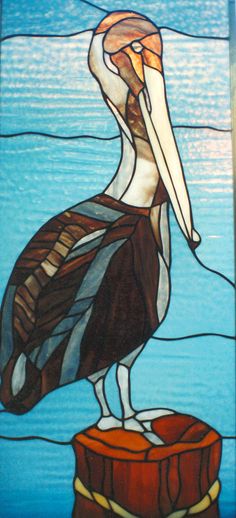 a stained glass window with a pelican sitting on top of a piece of wood