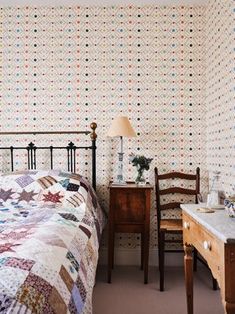 a bedroom with a bed, desk and chair in front of a wallpapered wall