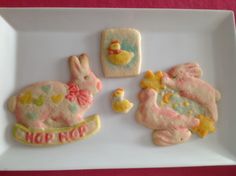 decorated cookies on a white plate with pink and yellow frosting in the shape of rabbits