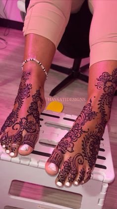 a woman with henna tattoos on her feet sitting on top of a white chair