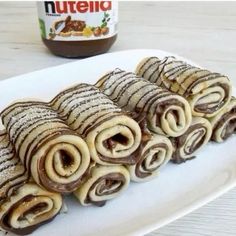 some kind of pastry on a white plate next to a jar of nutella spread