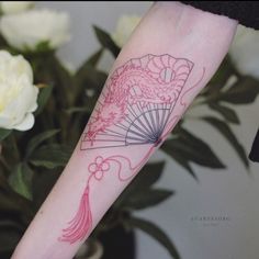 a woman with a tattoo on her arm holding a fan and flowers in the background