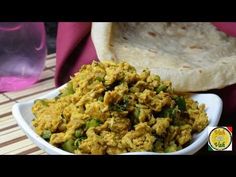 a white bowl filled with food next to a pita bread