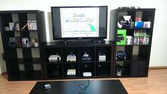 a flat screen tv sitting on top of a wooden shelf next to a black coffee table