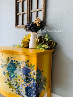 a yellow painted dresser with flowers on it