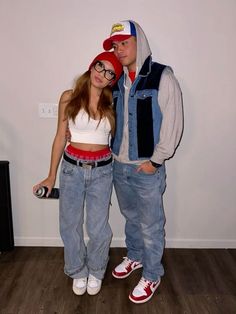 a man and woman standing next to each other in front of a wall with a camera