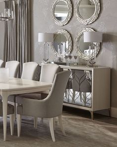 a dining room table and chairs with mirrors on the wall