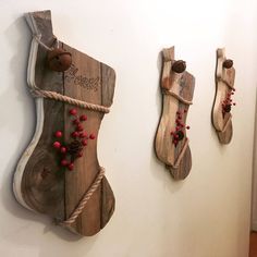 three wooden stockings hung on the wall with red berries and twine strings attached to them